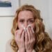 Woman with red, watering eyes holding a tissue during hay fever season — allergic conjunctivitis eye care in a UK independent optician practice.