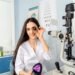 UK optician in a practice consulting room holding a trial lens beside a slit lamp — building a sellable, transferable independent optician business.