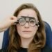 Optometrist adjusting trial frames during a sight test in a UK independent optician practice — the patient relationship as the real business asset.